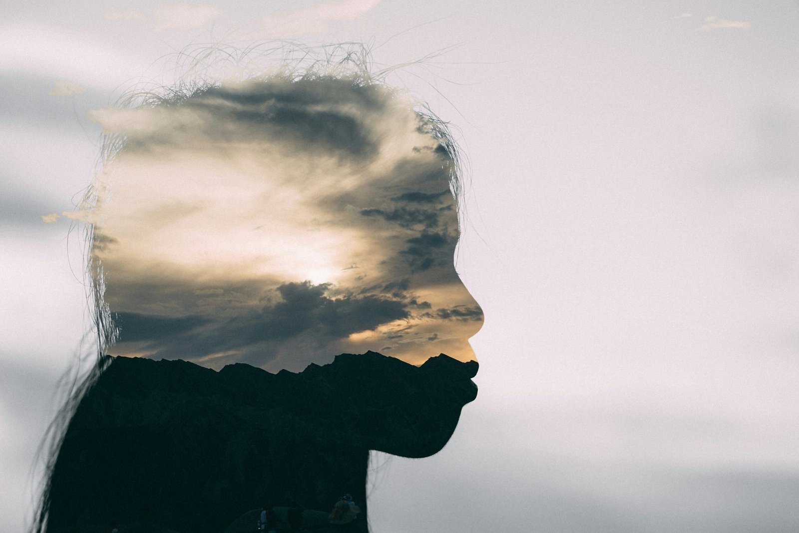 Silhouette d’une personne sous un ciel nuageux, symbolisant la perception unique et la sérénité liée à l’aphantasie. Photo de Nick Chen sur Unsplash.